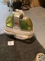 Side view of Bissell SpotBot with translucent green water tanks and hose coiled in front.