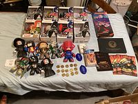 Photo of multiple vinyl collectible figures from Star Wars, Marvel, and Transformers including boxed and loose items, collectible coins, and music memorabilia spread on a bed.