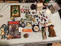 Overview photo of all collectibles including keychains, figurines, vintage magazines, and statuettes arranged on a bedspread.