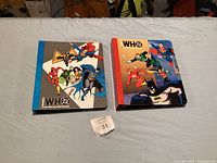 Front covers of two Who's Who binders showing various DC superheroes including Superman, Batman, Flash, and Wonder Woman.