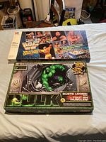 Two vintage board games on a white table: WWF Wrestling Challenge and Hulk-themed game.