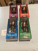 Lot of four Kiss collectible statuettes in original boxes representing Paul Stanley, Gene Simmons, Ace Frehley, and Peter Criss.
