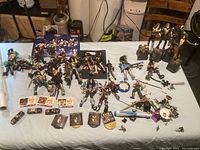 Wide tabletop shot showing the full assortment of Kiss collectibles including figures, miniatures, props, and memorabilia spread out.