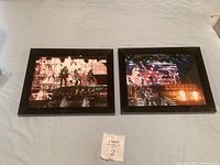 Two framed Kiss concert photos laid on a surface showing different views and lighting effects