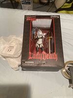 Photo of Lady Death figurine in original box from front showing figure and accessories through window.