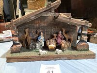 Front view of wooden nativity manger with all figurines arranged within stable.