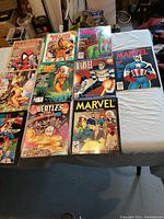 A collection of ten Marvel and related magazines on a table, with covers showing various Marvel characters including Spider-Man, Captain America, and swimsuit specials.