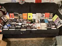 Full view of 26 music-related books arranged on a dark couch, showcasing titles and cover art.