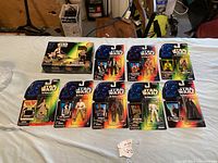 Lot of Star Wars action figures and Speeder Bike boxed vehicle on display on table.