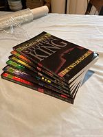 Side view of six Stephen King books stacked, showing spines and thickness.