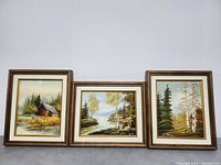 Three framed vintage oil paintings with landscape themes, displayed side-by-side against a white wall.