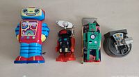Four vintage metal toy robots arranged side-by-side showing their front and side profiles