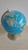Blue vintage globe showing North America on a metal base with a metal meridian scale.