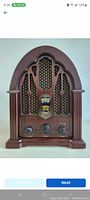 Front view of vintage GE cathedral style radio showing wood casing, grille, tuning window, and control knobs.