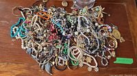 Wide view of assorted tangled vintage custom jewelry including bracelets, necklaces, earrings, chains, pins, and napkin rings, showing the variety and quantity in the lot.