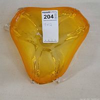 Top view of the amber yellow triangular art glass centerpiece with smooth glossy finish.