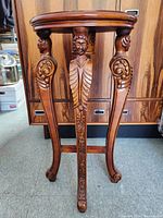 Full front view of the vintage walnut queridon table leg and apron detail showing carved Elizabethan courtly men's bust and scroll motifs.