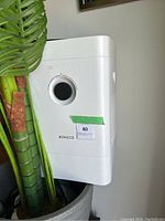 Side and front angled view of Boneco air purifier and humidifier unit beside a plant, showing white body with circular opening and Boneco logo.