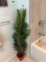 Full view of the artificial palm plant standing approximately 60 inches tall next to bathroom fixtures showing multiple large green palm fronds.
