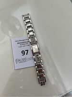 Top view of Guess women's silver tone bracelet watch laid flat on a surface showing the rectangular watch face and linked metal bracelet.