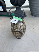 Photo showing decorative metal hanging lantern with floral cutout design and curved metal handle.