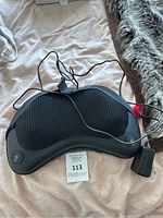 Black heated shiatsu massage device laid on a surface with attached wired remote control, showing overall condition and components.