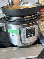 Front view of Instant Pot electric pressure cooker showing the lid and control panel with some buttons visible.