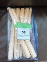 Seven cream tapered candlesticks packaged in a clear plastic bag, arranged side by side, all unused and new.
