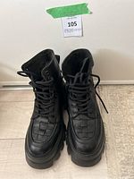 Front view of the Nubikk black leather combat boots showing woven toe detail and laces