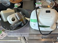 Omega juicer motor unit with accessories including white plastic and metal juicing cones, clear plastic chute, and collection cups with visible turmeric stains.
