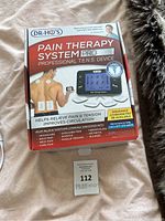 Photo of the Dr. Ho's Pain Therapy System Pro device in its original box displaying product features and benefits.