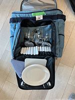 Open view of cooler bag showing wine glasses, cutlery, plates, and napkin inside.