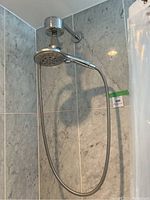Full view of shower system installed on tiled wall, showing flexible metal hose and dual shower heads.