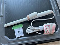 Top view of T3 curling iron laid flat showing full length with cord and safety warnings.