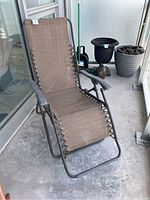 Brown zero gravity chair on a balcony with metal frame and fabric seating, laced sides, showing condition and features.