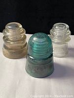 Three antique glass insulators against black background showing all items
