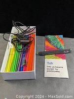 3Doodler pen, colorful plastic strands, power adapter, and instruction guide in white box