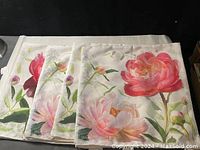 Four floral zip-up throw pillow covers laid out showing the colorful floral front design with pink and red flowers, green leaves, and white background.