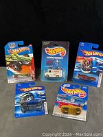 Five assorted Hot Wheels cars in original sealed packaging with blue branded card backs.