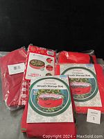 Photo shows four red Christmas wreath storage bags, still in original packaging, labeled as 30 inch capacity wreath bags.