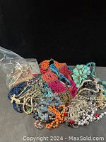 Overall view of tangled beaded necklaces including colorful plastic beads, faux pearls, metal chains, and turquoise flower beads