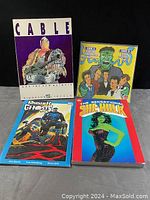 Photo of four comic and cartoon books including Cable and the New Mutants, She-Hulk, Punisher Ghosts, and a cartoon album