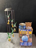 Photo showing two hummingbird chimes, the inflatable beach ball in its retail box, and the hanging ceramic pot.