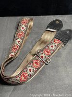 Photo showing the full guitar strap, displaying woven floral fabric strap with leather ends and metal adjustment buckle.