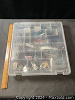 Top view of closed transparent plastic organizer box with multiple compartments visible inside, approximately 12" x 12" in size, shown next to a ruler for scale.