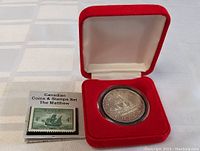 Silver dollar coin displayed in protective round case inside red velvet presentation box.