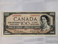Full front view of 1954 Canada $100 note showing portrait of Queen Elizabeth II, serial numbers, signatures and bilingual text.