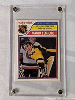 Front of Mario Lemieux rookie scoring leader card in protective case showing player image and title text