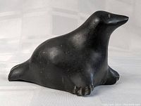 Side view of the black soapstone carved seal, showing smooth polished surface and flipper details.