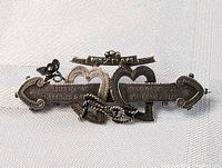 Close-up photo of the silver Mizpah brooch detailing the interlocking hearts and arrow with inscriptions.